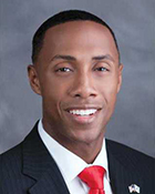 A headshot photo of a man wearing a suit and tie