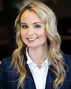 A headshot photo of a woman wearing a navy blue suit jacket