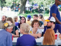 People wearing purple and gold attire sit at a table and talk