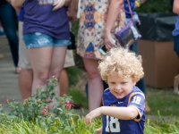 A young boy wearing an LSU football jersey runs through grass