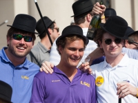 Three male students wearing black hats smile