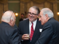 A man smiles as he talks to two other men