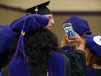 Two female students wearing graduation attire take a selfie
