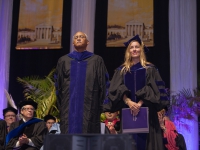 A man and a woman wearing graduation attire stands