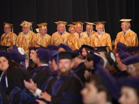 A group of people wearing yellow graduation robes