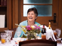 A woman is seated at a table and smiles