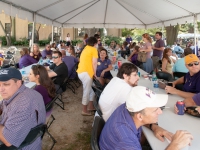 People wearing purple and gold attire sit at tables