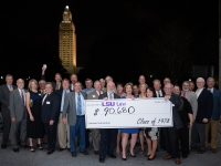 A group of people hold a large check for $90,680 with the Louisiana state capitol in the background.