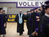 A man gives a high-five to a student wearing graduation attire