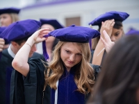 A female student wears a graduation robe and cap