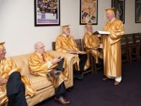 A group of men wearing gold robes talk to each other