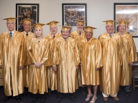 A group of people wearing gold robes poses for a photo