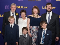 A group photo of seven people wearing semi-formal attire with the LSU Law logo in the background