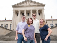 Two men and two women smile for a photo with the LSU Law Center in the background