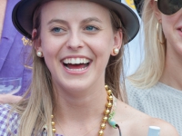 A woman wearing a derby hat smiles