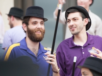 Two men wearing derby hats talk to each other