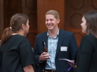 A male student smiles as he talks to two female students