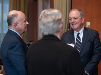 A man wearing a suit and tie talks with two other people