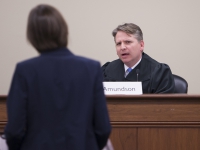 A man wearing judges robes talks to a female student