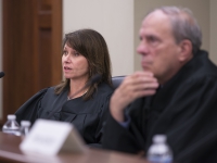 A woman in judges robes speaks with another judge in the foreground