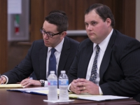 Two male students wearing suits and ties sit at a table and take notes