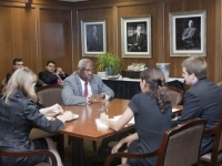 Two men and two women sit at a square table and talk