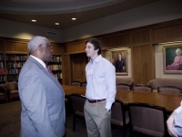 A man wearing a suit and tie talks to a student