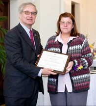 A man hands a woman a plaque as they smile for a photo