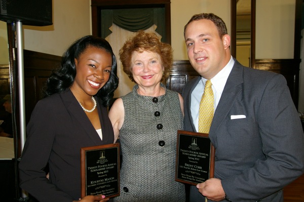 Two women and a man pose for a photo with one woman and one man each holding a wooden plaque