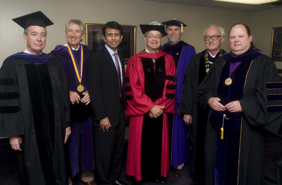 Seven men wearing caps and gowns pose for a photo before the LSU Law Center Commencement