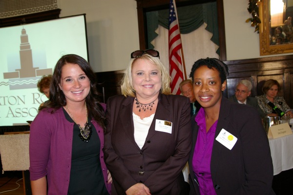 Three women pose for a photo with the Baton Rouge Bar Association logo in the background