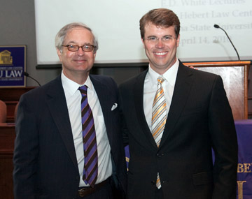 Two men in suits and ties pose for a photo together