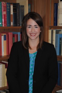 A female smiles for a photo with books in the background