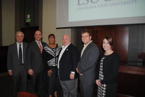 Four men and two women wearing business attire smile for a group photo