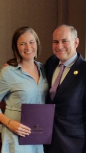 A female student and a male professor smile for a photo