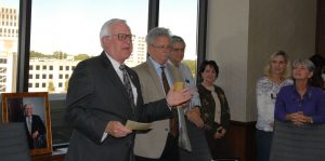 A man in a suit and tie addresses a gathering of people