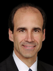 A headshot photo of a man wearing a suit and tie