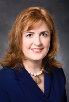 A headshot photo of a woman wearing a blue suit jacket
