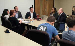 A group of people sit around a table in a classroom