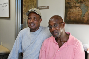 Two men pose for a photo with a map in the background