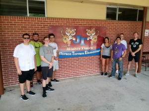 A group of people pose for a photo outside of a school
