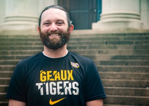 A male student stands on the steps of the LSU Law Center