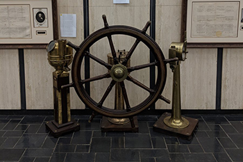 A ship wheel and other instruments with shipping passports in background