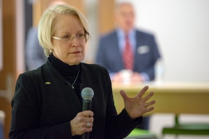 A woman holds a microphone and speaks