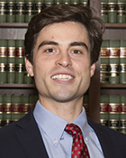 A headshot photo of a man in a suit and red tie