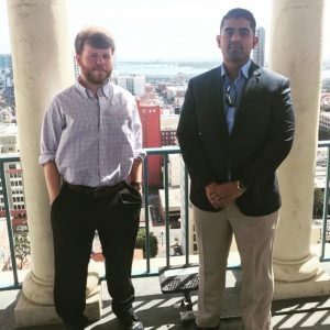 Two male students stand on a balcony for a photo